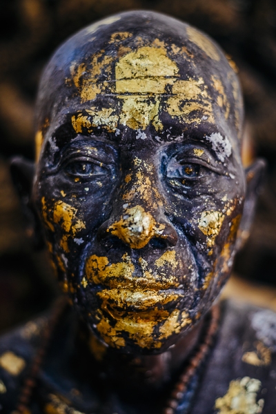 Dramatic close-up of Buddhist statue with the gold foil peeling off.